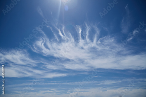 Cirrus clouds in blue sky with sunbeams in frame