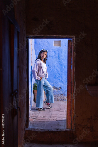 A teen stands in front of a blue door