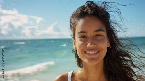 Portrait of a young woman smiling by the sea on a sunny day
