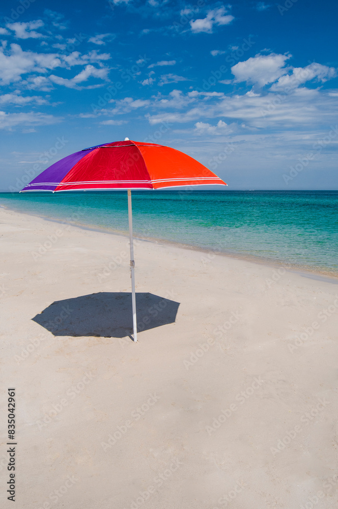 A colorful umbrella on the white sand of the beach with a blue and transparent sea, on EL TECOLOTE beach in the so-called Puerto de Illusion. La Paz Baja Mexico A colorful umbrella on the white sand of the beach with a blue and transparent sea, on EL TECOLOTE beach in the so-called Puerto de Illusion. La Paz Baja Mexico