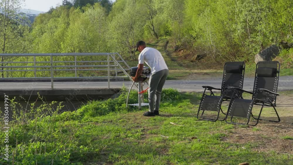 Man setting up bbq dinner at campground in Norway, afternoon sunshine