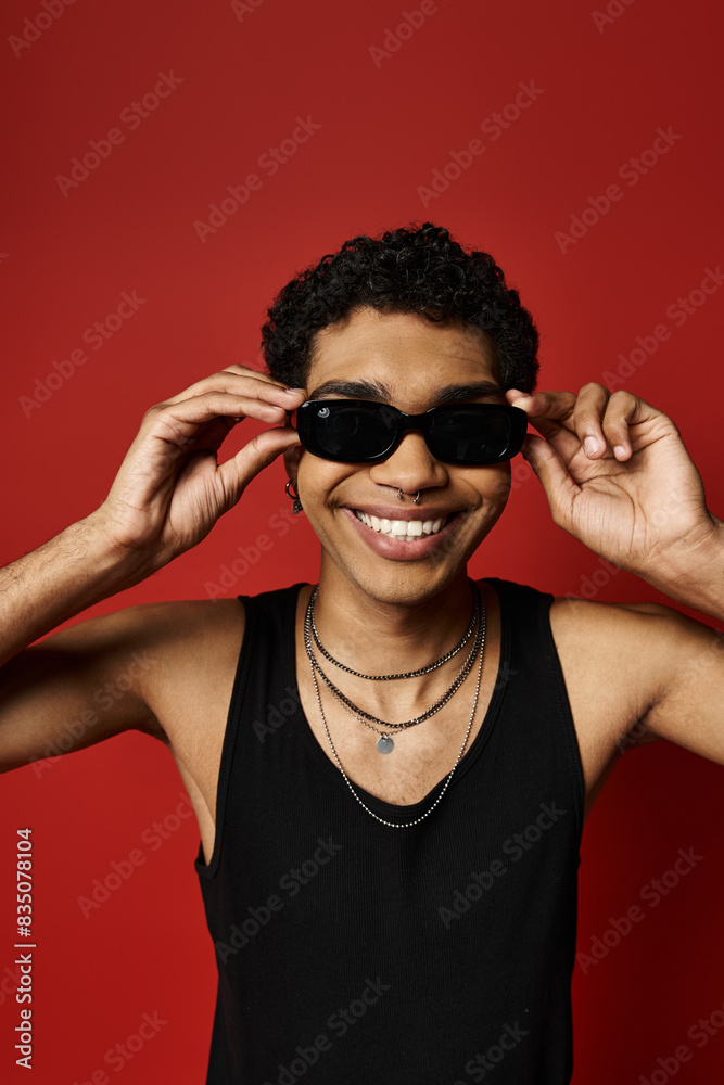 Handsome young African American man in stylish sunglasses against a vibrant red backdrop. Handsome young African American man in stylish sunglasses against a vibrant red backdrop.