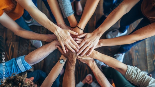 A group of diverse people joining their hands together over wooden background, top view. Unity and teamwork concept.