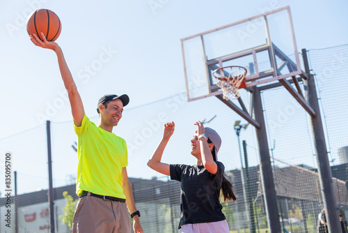 A father and daughter playing basketball in the park