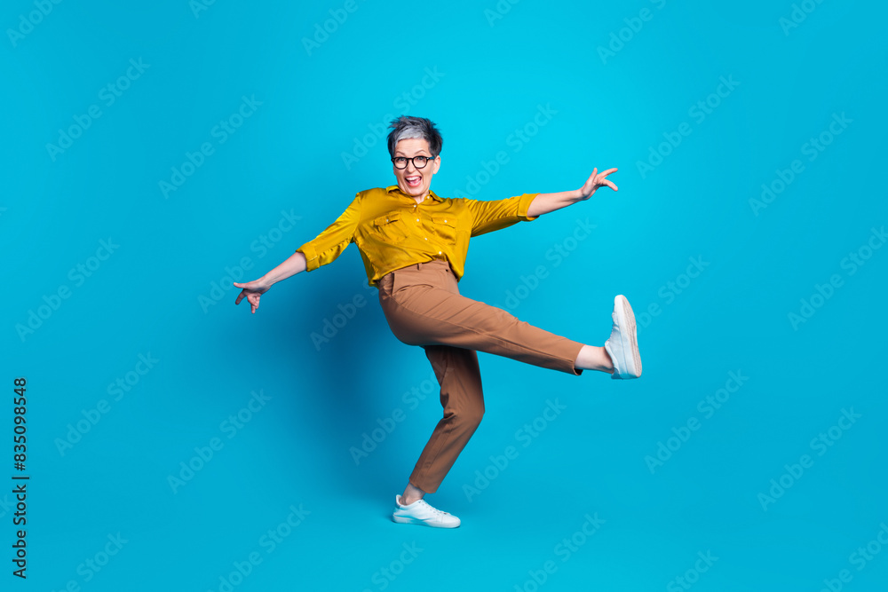 Full length photo of adorable good mood lady dressed shirt eyewear having fun empty space isolated blue color background Full length photo of adorable good mood lady dressed shirt eyewear having fun empty space isolated blue color background