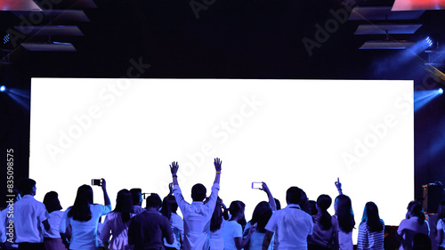 Front view of mockup on big blank white screen with space in empty huge hall with enjoy and happy audiences.