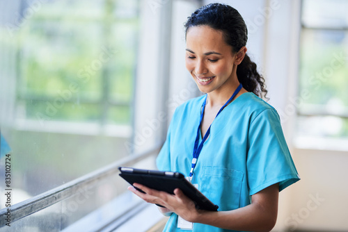 Smiling Nurse in Hospital Scrubs Using Digital Tablet in Modern Medical Facility