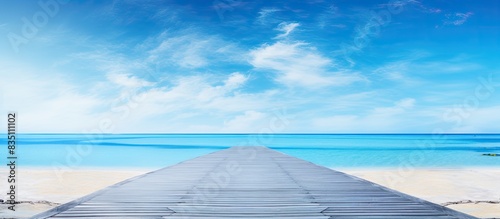 An empty asphalt road with copy space image borders a serene beach under a clear blue sky. © vxnaghiyev