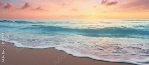 A breathtaking image of a serene beach at sunset with ocean waves, offering a peaceful paradise vibe and plenty of copy space image.