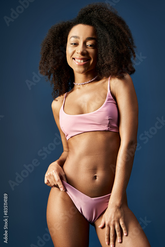 Young African American woman posing confidently in trendy pink bikini.