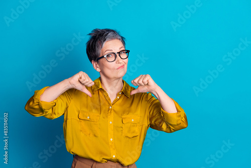 Photo of confident attractive lady dressed shirt glasses showing thumbs herself emtpy space isolated blue color background © deagreez