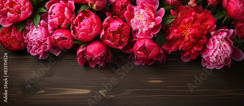 Fototapeta Naklejka Na Ścianę i Meble -  Pink and red peonies positioned beautifully on a rustic wooden backdrop with space for text or graphics in the frame. with copy space image. Place for adding text or design