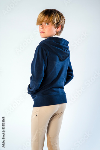 Horse rider athlete in a blue hoodie and equestrian pants casually looking over his shoulder photo
