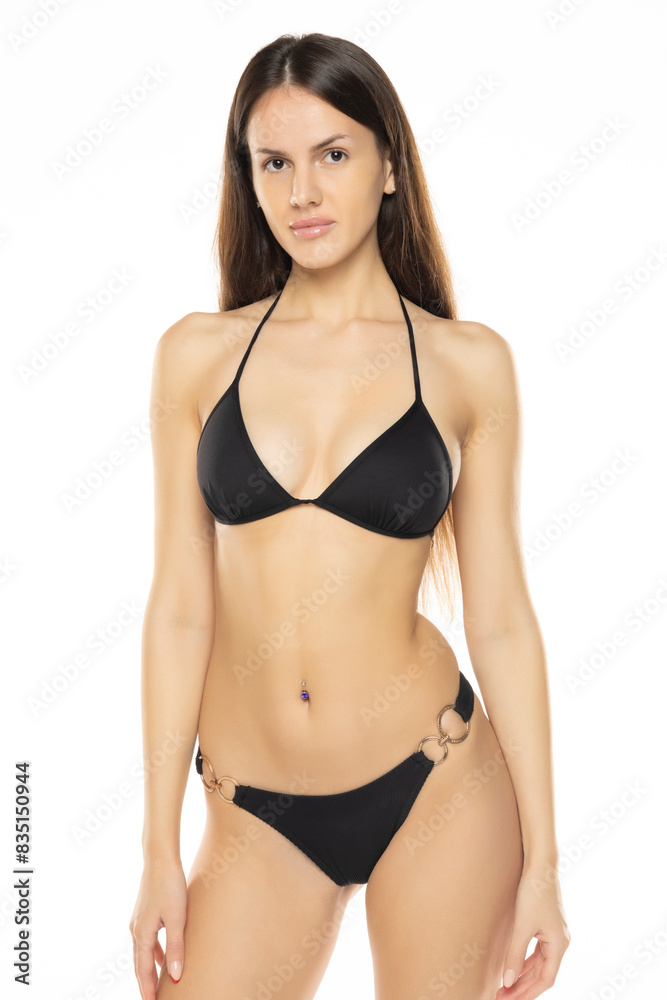 Young brunette woman in bikini swimsuit posing on a white studio background. Front view Young brunette woman in bikini swimsuit posing on a white studio background. Front view