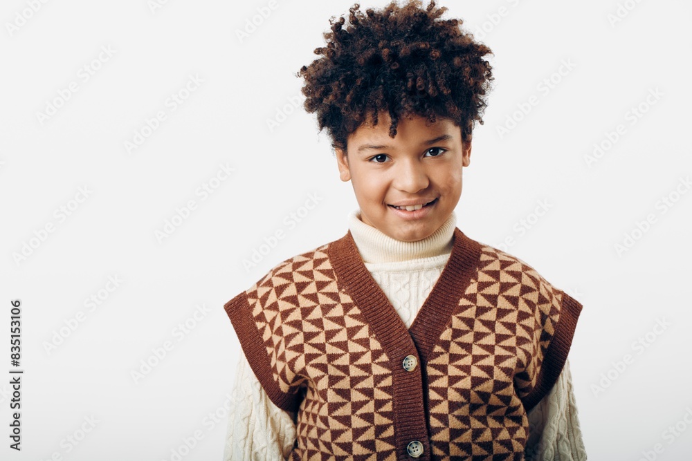 A young african american boy dressed in a cozy brown sweater and white turtleneck smiling brightly against a neutral background A young african american boy dressed in a cozy brown sweater and white turtleneck smiling brightly against a neutral background