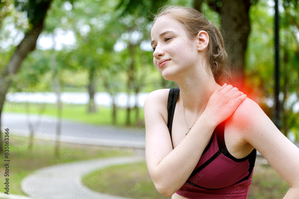 young woman in sports bra touches her shoulder in pain or injury while jogging in a park at the morning. fitness, health, injury, exercise and outdoor activities. young woman in sports bra touches her shoulder in pain or injury while jogging in a park at the morning. fitness, health, injury, exercise and outdoor activities.