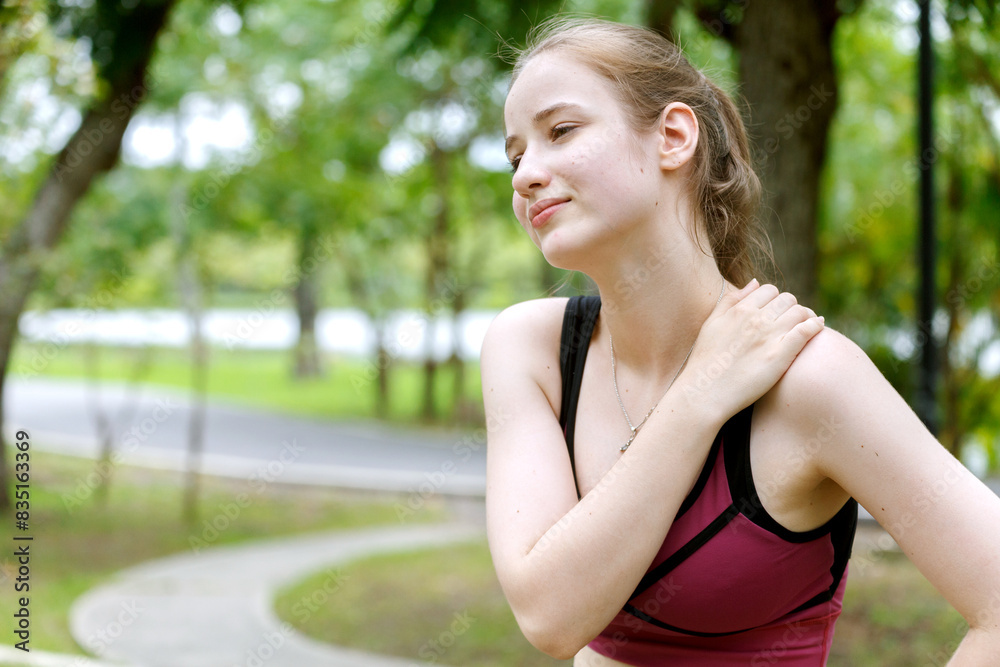 young woman in sports bra touches her shoulder in pain or injury while jogging in a park at the morning. fitness, health, injury, exercise and outdoor activities. young woman in sports bra touches her shoulder in pain or injury while jogging in a park at the morning. fitness, health, injury, exercise and outdoor activities.