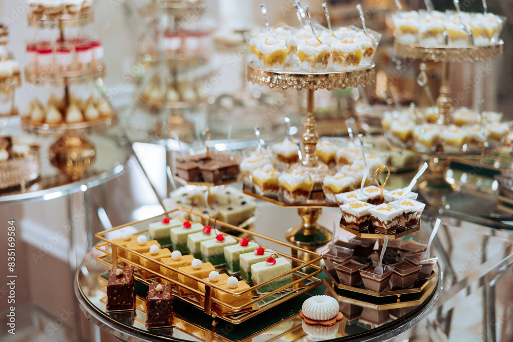 A table full of desserts with a variety of flavors and colors. Scene is celebratory and indulgent, as it is a dessert buffet for a special occasion