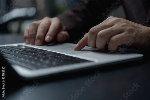 A person is typing on a laptop with a finger pointing to the screen