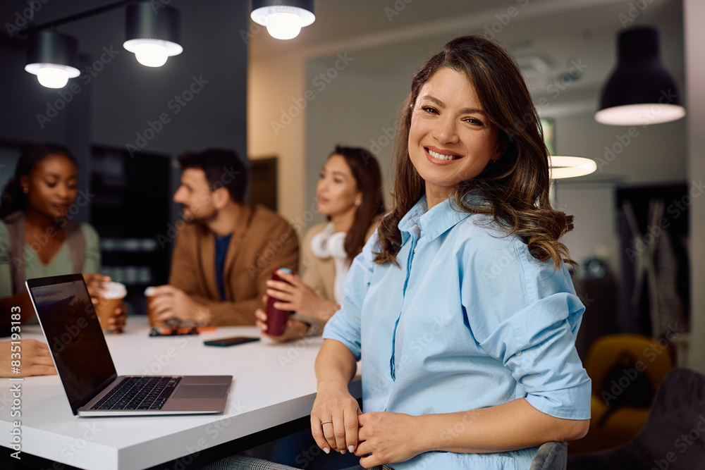 Happy entrepreneur using laptop during coffee break with her colleagues and looking at camera. Happy entrepreneur using laptop during coffee break with her colleagues and looking at camera.