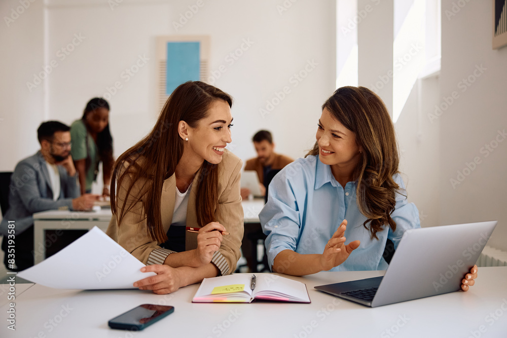 Happy female colleagues cooperating while working on laptop in office. Happy female colleagues cooperating while working on laptop in office.