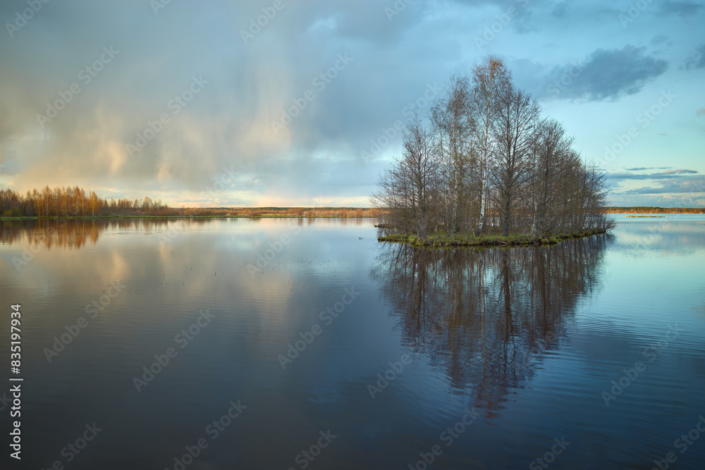 Nature of Northern Europe: lake before sunset, island, rainbow, colorful clouds with reflection, May. Nature of Northern Europe: lake before sunset, island, rainbow, colorful clouds with reflection, May.