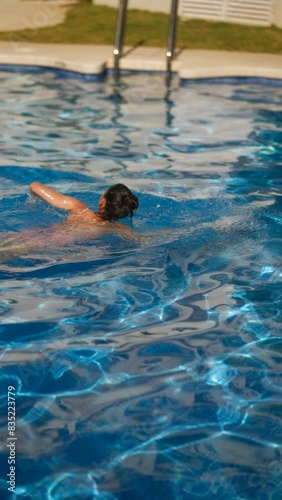 A woman peacefully swimming in an outdoor pool on a sunny day, enjoying tranquility and relaxation photo