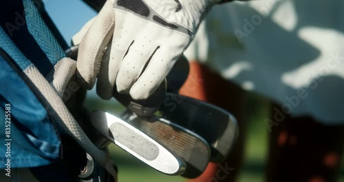 Close-up shot of a young female professional golfers glove hand selecting a club to play from a golf bag. Sports equipment for playing golf. Country Club.