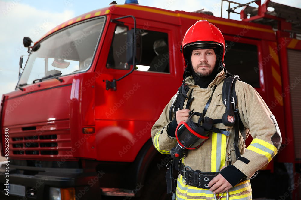 Firefighter in uniform near red fire truck at station