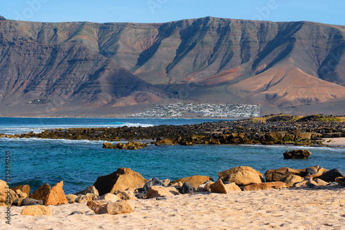 View of Playa de Famara in village La Caleta, Lanzarote, Canary Islands, Spain with mountains on the background. photo