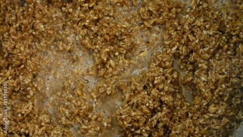 Malt mash is stirred with a large spoon during brewing