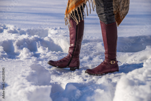 Slender women's legs in beautiful  high leather boots on the snow.