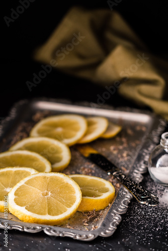 Lemon slices on a silver tray with salt and knife