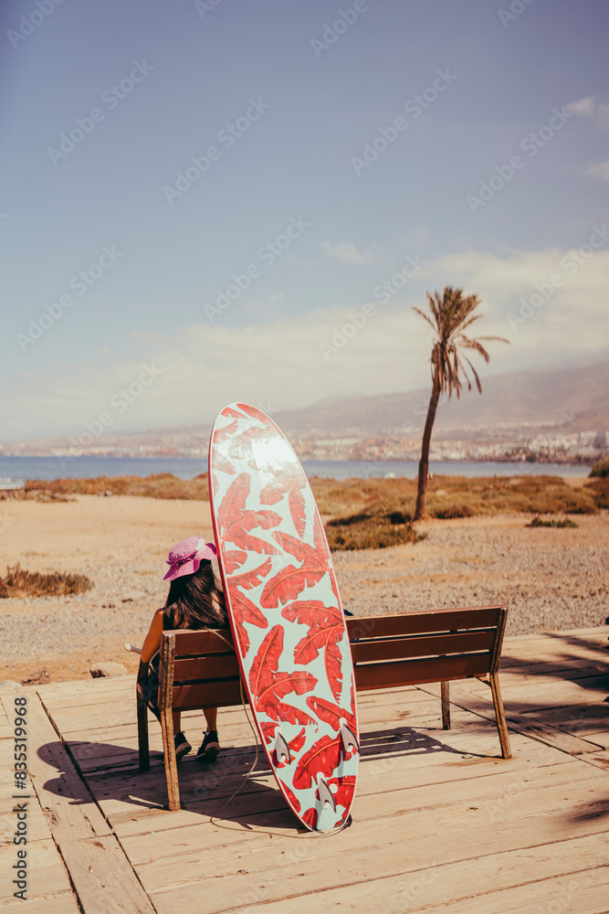 silueta de surfista esperando sentado junto a su tabla en la playa de tenerife