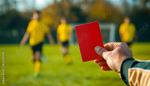 Referee hand with red card and blur soccer player in background photo