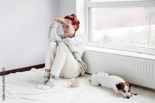 Obraz na plátně Sad young Woman sitting near radiator at home