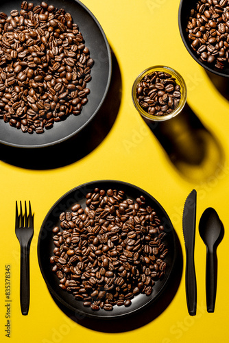 Overhead table setting with coffee beans in all the dishes on a yellow background, coffee concept, bold