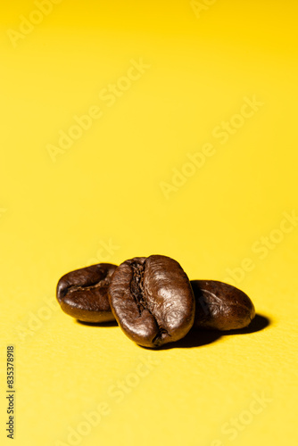 Three coffee beans close up isolated on a yellow surface background
