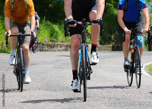 Three cyclists with racing bikes pedal on the asphalt road photo