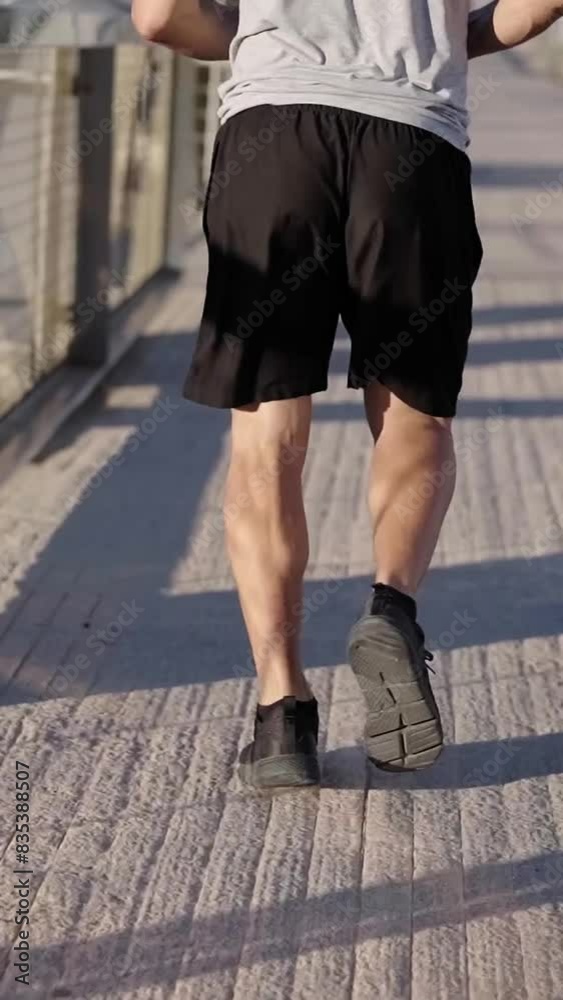 Rear view vertical video going from the feet to the head of a sport mature man running outdoors in the morning self-disciplined to be healthy and strong. Copy space. Rear view vertical video going from the feet to the head of a sport mature man running outdoors in the morning self-disciplined to be healthy and strong. Copy space.