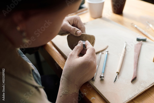 High angle view of unrecognizable woman with Down syndrome making ceramic bowl during pottery class in workshop