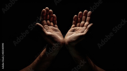 Praying hands against dark background in stock image