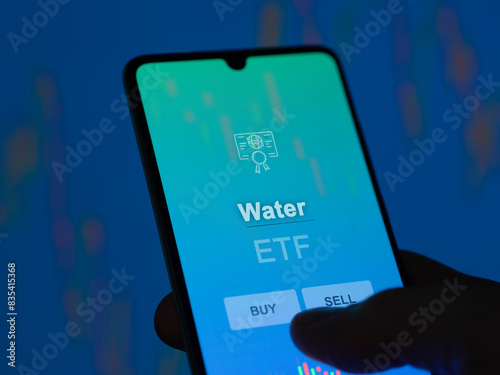 An investor analyzing the water etf fund on a screen. A phone shows the prices of Water photo