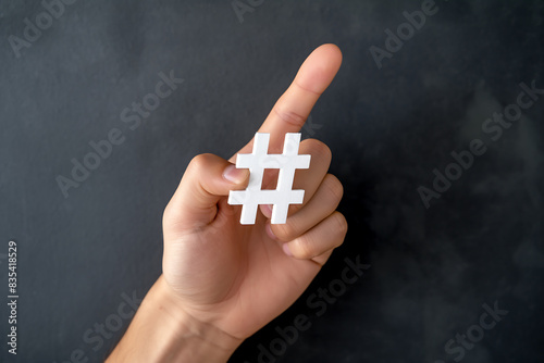 Hand holding hashtag symbol on blackboard background representing social media trends digital marketing online engagement modern communication and popular content sharing