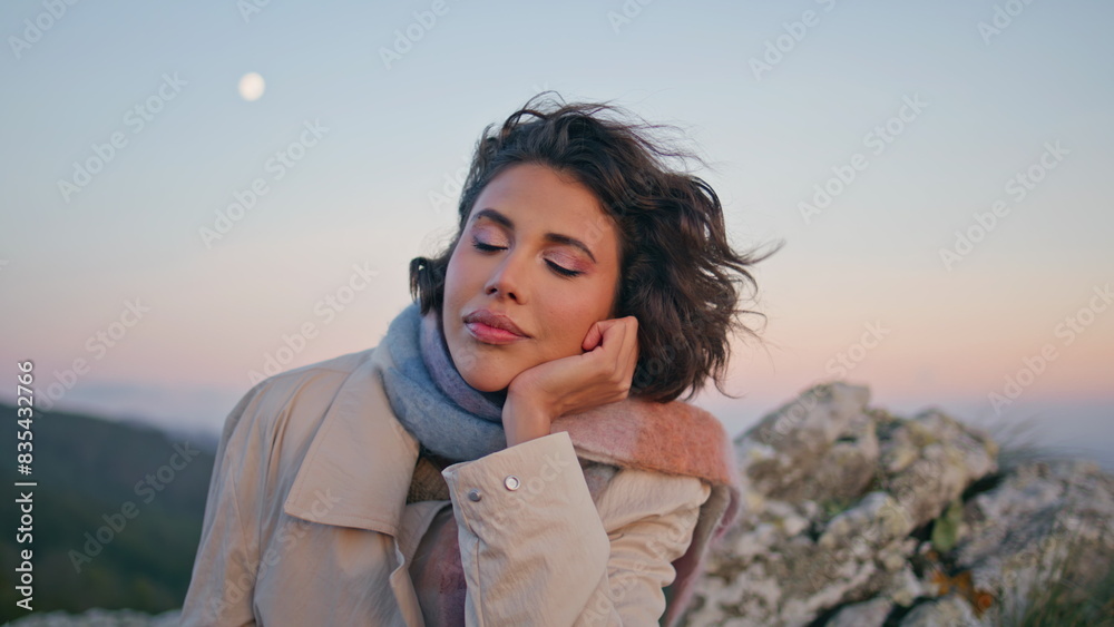Thoughtful woman posing rocks in front evening sky closeup. Curly traveler 