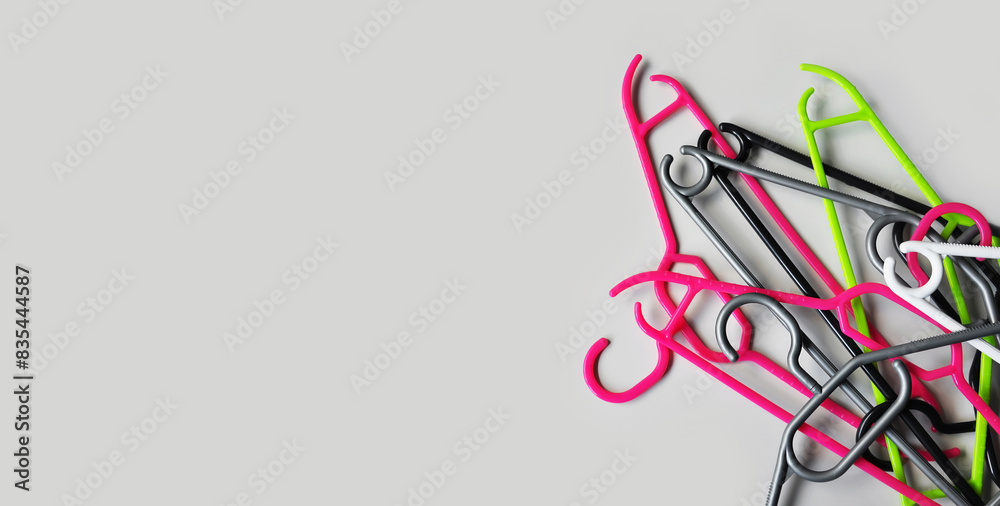 Stacked empty plastic clothes hangers on a light gray background. Minimalism. The concept of modern consumption. Copy space