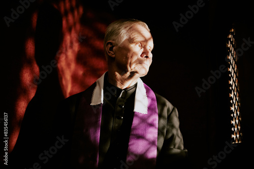Photos Medium closeup of senior Caucasian Catholic priest hearing out penitent in confe