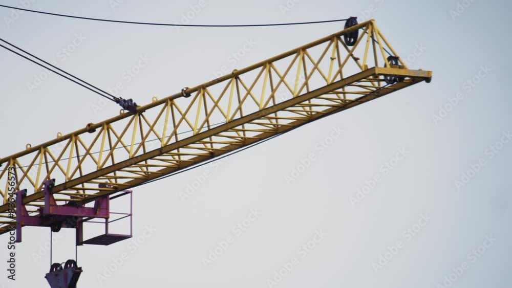 Silhouetted against a muted sky, a yellow crane carries a platform, embodying the essence of ongoing development. Silhouetted against a muted sky, a yellow crane carries a platform, embodying the essence of ongoing development.