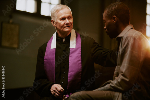 Photos Selective focus shot of senior Caucasian priest sitting on pew supporting sad Af