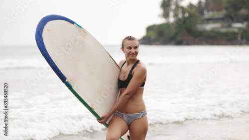 Portrait with a summer mood. Surfing, lifestyle, recreation, vacation. Charming girl with a surfboard